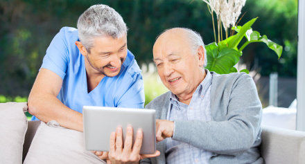 caregiver and senior man busy with a tablet