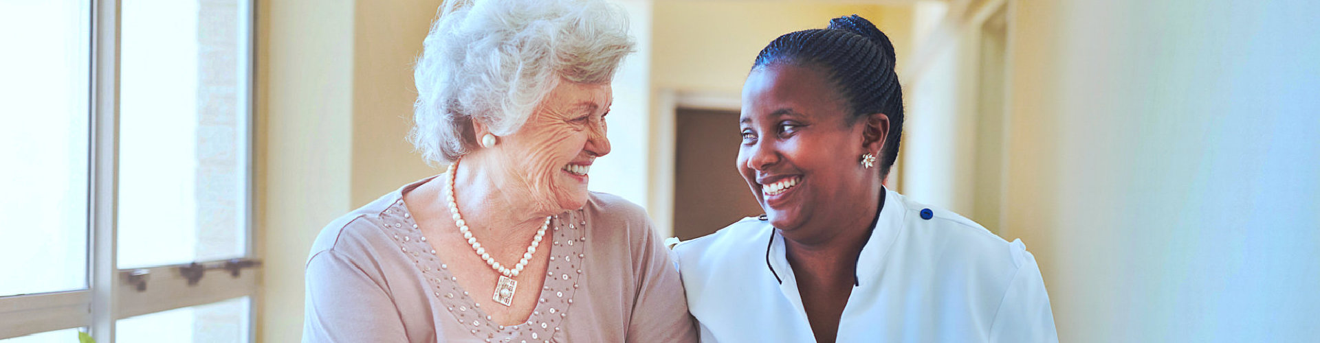 senior woman and caregiver smiling