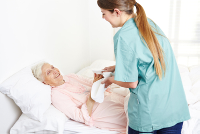 Caregiver helping senior woman in bed